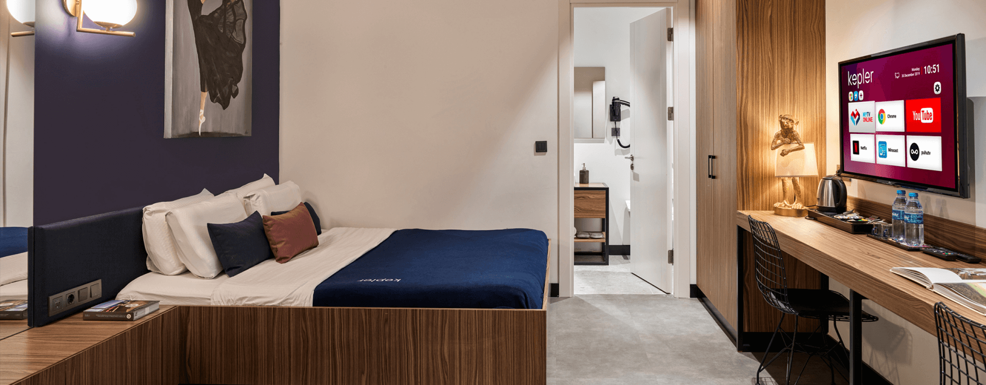 Photo of a hotel room with a king size bed and smart TV, offering a warm, welcoming, luxurious, elegant, and clean environment.